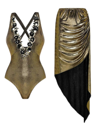 Vorderansicht des metallisch-goldenen Badeanzugs, kombiniert mit einem dazu passenden, drapierten Sarong mit schwarzen Fransen.