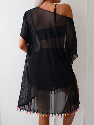 Schwarzes schulterfreies Kleid mit bunten Quasten auf schlichtem Hintergrund