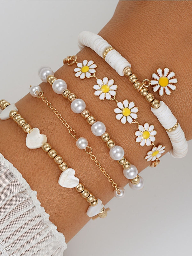 Ein Set aus stapelbaren Armbändern im Boho-Stil mit zarten Gänseblümchen-, Perlen- und Herzperlen, das sommerlichen Festival-Outfits oder lässiger Alltagskleidung eine verspielte Note verleiht.