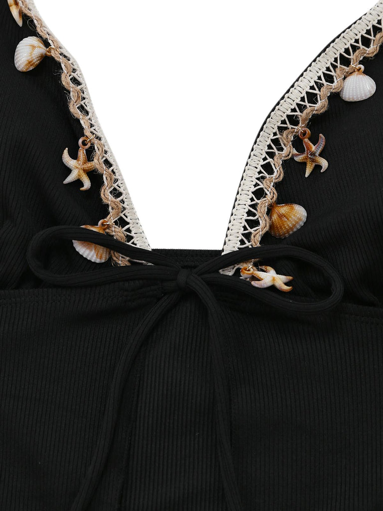 Schwarzes Kleid mit weißer Spitzenborte und Muschelverzierungen auf weißem Hintergrund