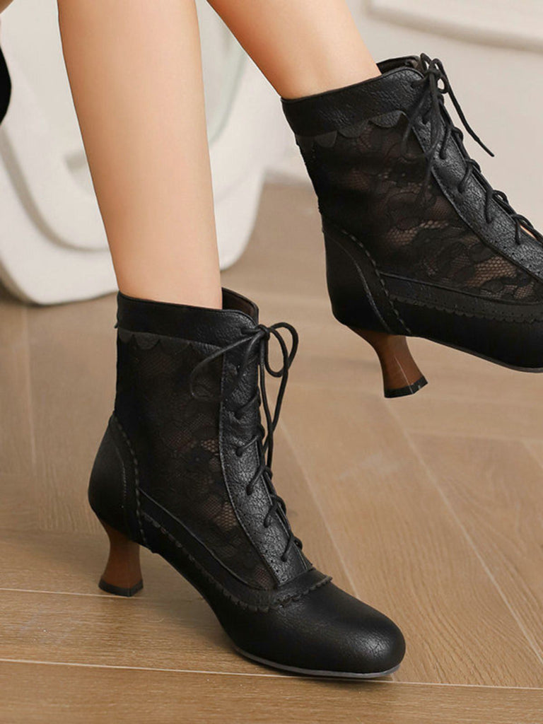 Schwarze Schnürstiefel mit hohem Absatz auf einem Holzboden.
