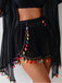 Schwarze Shorts mit bunten Quasten auf einfarbigem Hintergrund