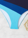 Blau-weißer Badeanzug auf strukturierter Oberfläche mit einem goldenen geometrischen Objekt.