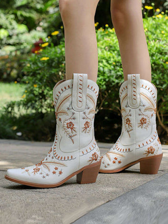 Weiße Cowboystiefel mit Blumenstickerei vor verschwommenem Hintergrund im Freien