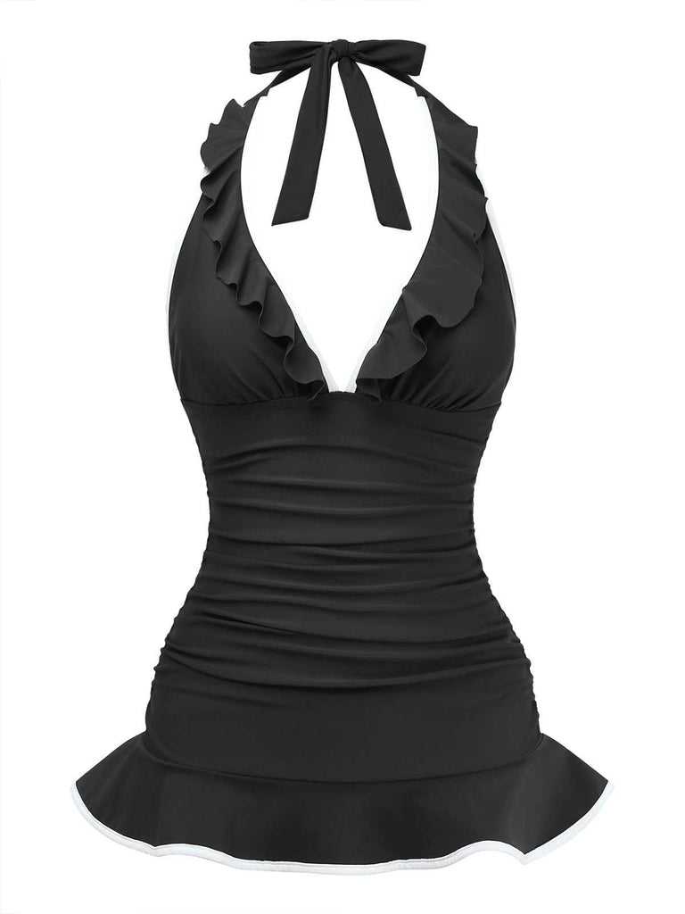 Studioaufnahme von vorne des schwarzen Neckholder-Badeanzugs mit tiefem V-Ausschnitt und Rüschen sowie einem schmeichelhaften, ausgestellten Saum im Skater-Stil.