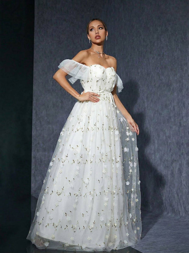 Frau in einem weißen, geblümten, schulterfreien Kleid vor dunklem Hintergrund