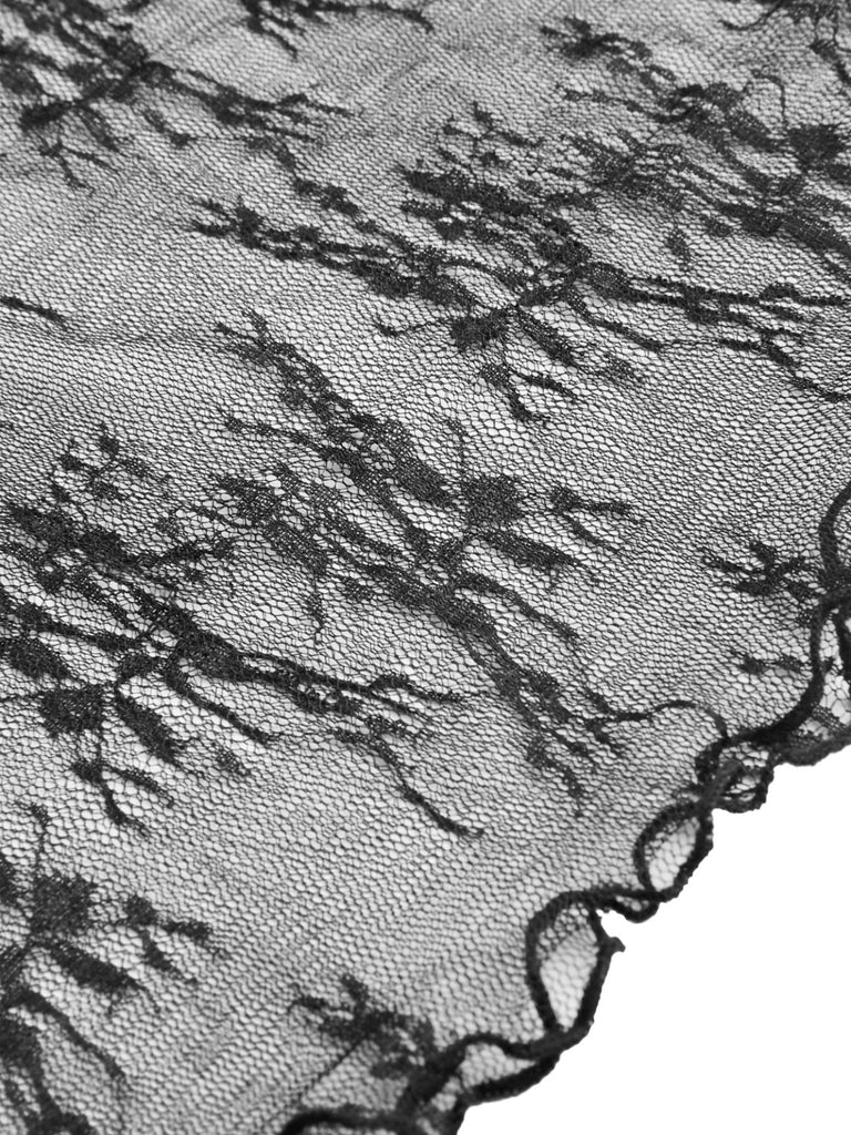Nahaufnahme des zarten, transparenten Spitzenstoffs mit Blumenmuster und der gewellten Kante des langärmeligen Oberteils.
