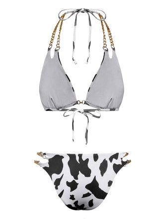 Rückansicht des schwarz-weißen Bikinis mit Kuhmuster, die die Bindebänder und die goldenen Kettenriemendetails zeigt.