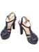 Ein Paar marineblaue High-Heel-Sandalen im Retro-Stil mit verstellbaren Knöchelschnallen und klassischem T-Riemen-Design.