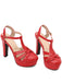Ein Paar auffällige rote High-Heel-Sandalen mit klassischem T-Riemen und stabilem Plateau.