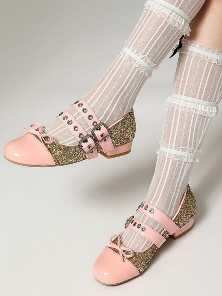Pinkfarbene Glitzerschuhe mit goldenen Schnallen, getragen mit hauchzarten weißen Strümpfen auf hellgrauem Hintergrund