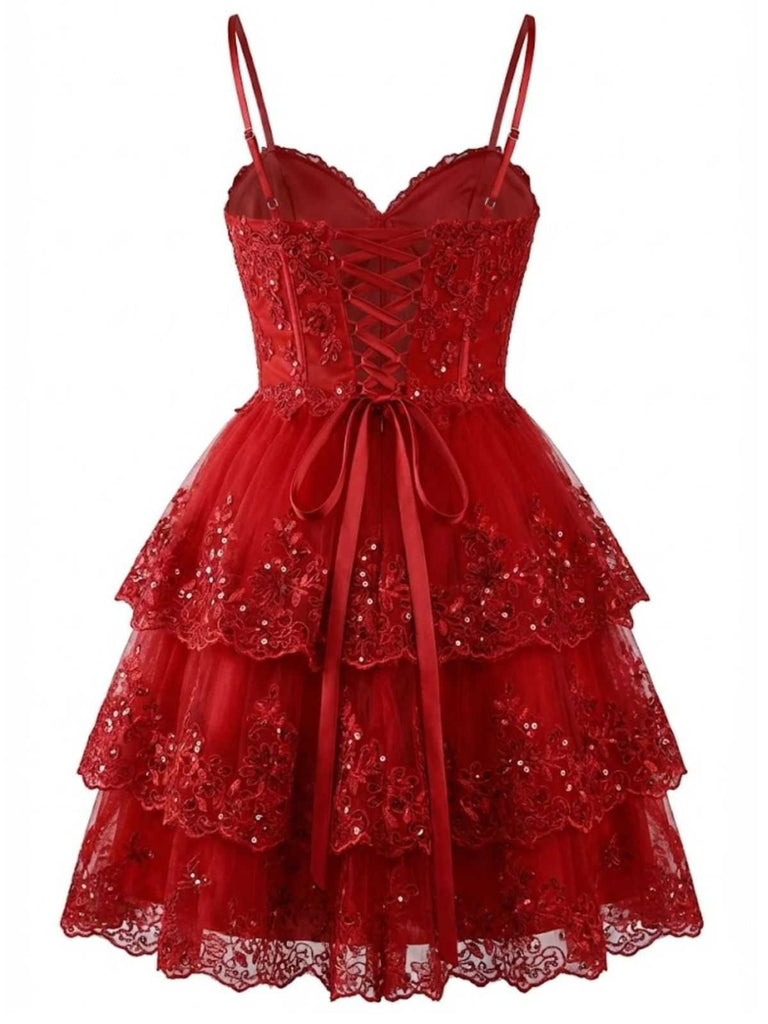 Studioaufnahme von vorne, die das rote Spitzen-Partykleid mit den Spaghettiträgern und dem mehrlagigen Netzrock hervorhebt.