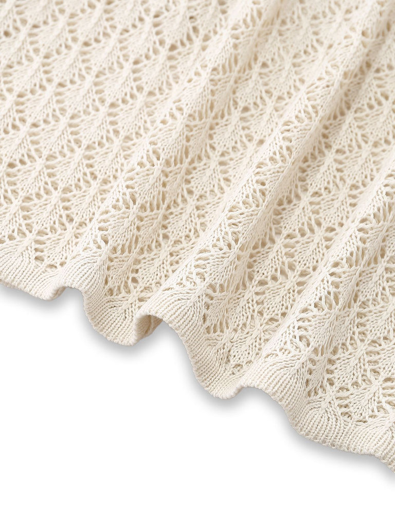 Eine Nahaufnahme, die den Saum und die detaillierte Strickarbeit des cremefarbenen Häkel-Überwurfs zeigt.