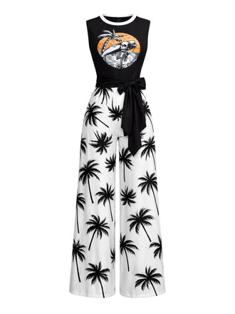 Ein schwarz-weißer, ärmelloser Jumpsuit mit Palmenmuster auf der weiten Hose und einer grafischen Strandillustration auf dem schwarzen Oberteil mit Bindegürtel.