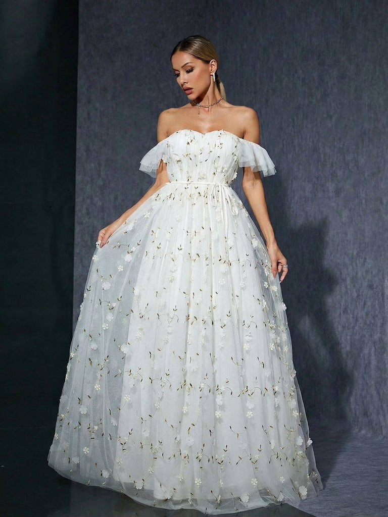 Frau in einem weißen schulterfreien Kleid mit floralen Details vor dunklem Hintergrund